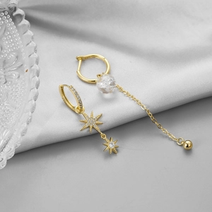 Macro detail of asymmetrical gold zircon earrings with star pendants and glass beads