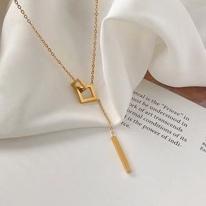Minimalist gold geometric Y-shaped necklace with interlocking squares on silk background