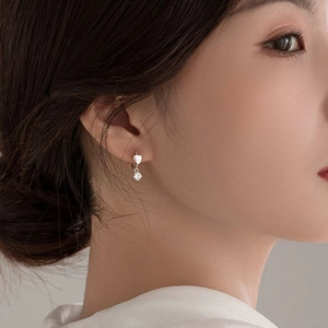 Close-up of S925 silver heart earring with a sparkling round zircon stone on model