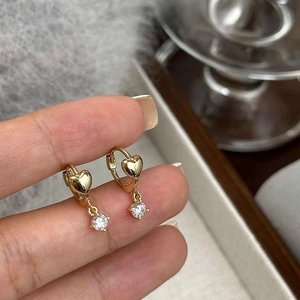 Detailed view of S925 silver heart hoop earring with round zircon pendant held by hand