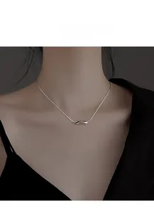 Gros plan d'un collier géométrique minimaliste argenté porté sur un haut noir