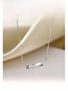 Gros plan d'un pendentif torsadé en argent sur une chaîne serpent minimaliste