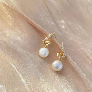Détail macro de boucles d'oreilles perles avec spirale dorée et cristaux brillants
