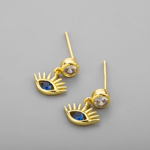 Vue macro de boucles d'oreilles œil maléfique dorées avec zircon bleu et détails