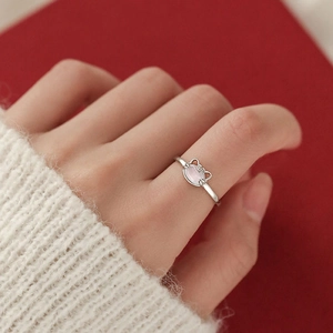 S925 silver cat-shaped ring with cat eye stone on hand against red background