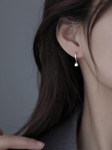 Detailed close-up of a minimalist S925 silver square charm earring worn on an ear