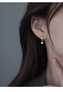 Close-up of minimalist S925 silver gold-plated hoop earring with a geometric cube charm