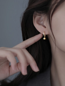 Close-up of minimalist gold S925 silver cube drop earrings worn by a female model