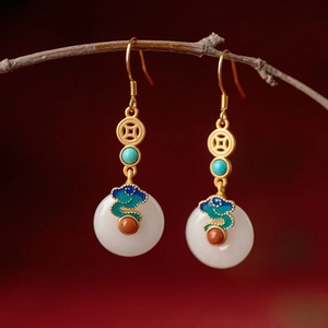 Detail of gold enamel earrings with jade ring and turquoise bead on wooden branch