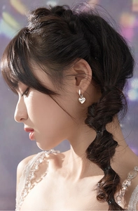 Gros plan de boucles d'oreilles cœur en argent poli sur modèle avec fond violet
