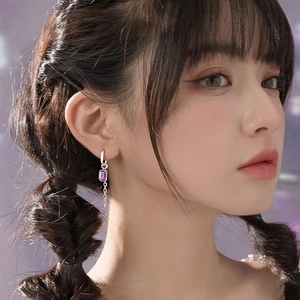 Boucles d'oreilles asymétriques en chaîne argentée avec cristaux violets sur un mannequin