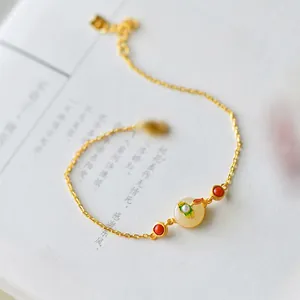 Detailed shot of a gold lotus bracelet with white Hetian jade and red agate beads