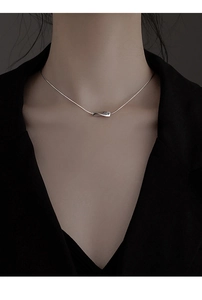 Détail du collier argenté avec pendentif géométrique torsadé sur une chaîne serpent fine