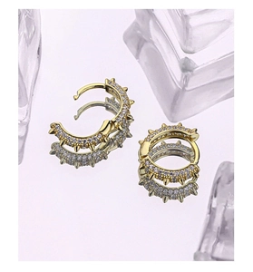 Detail of gold-plated punk hoop earrings with micro-paved zircons and rivet spikes
