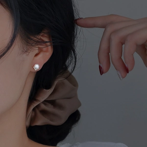 Close-up of S925 silver pearl earring with a diamond-set V-shape on a model ear