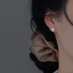 Close-up of S925 silver pearl earring with V-shaped diamond setting worn by a model
