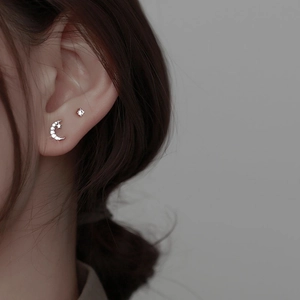 Asymmetric S925 silver moon and star stud earrings set on female model ear