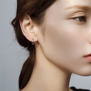 Minimalist S925 sterling silver twisted rope hoop earrings worn by a model on a blue background