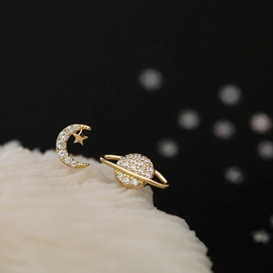 Macro shot of asymmetric s925 silver crescent moon and planet studs with cubic zirconia