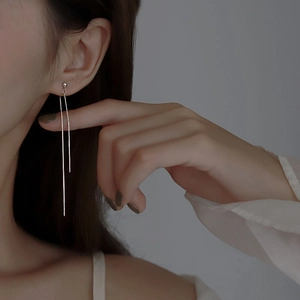 Détail macro d'élégantes boucles d'oreilles pendantes en argent portées par un mannequin