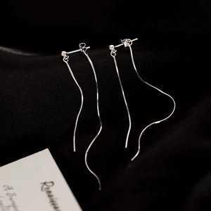 Détail de boucles d'oreilles pompon en argent S925 sur un fond de tissu en soie noire