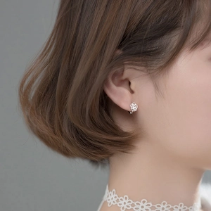 Close-up of a hollow rose earring in s925 silver worn on a woman's ear for a dainty look
