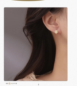 Macro detail of gold S925 silver hollow rose earrings on model's ear