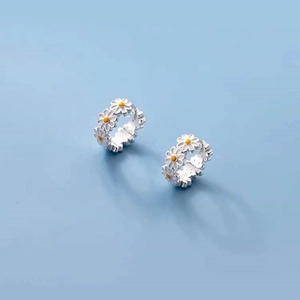 Close-up of S925 sterling silver daisy hoop earrings with white enamel petals and yellow center