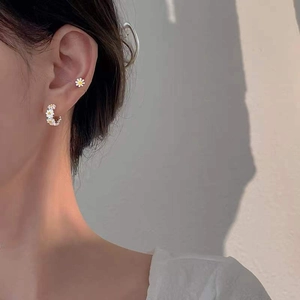 Detailed view of S925 silver daisy hoop earrings and studs worn on a model's ear