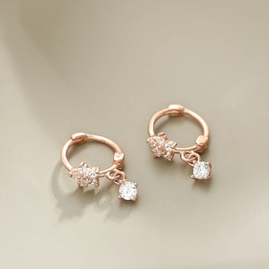 Macro view of rose gold floral huggie earrings featuring sparkling zircon stone drops