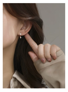 Close-up of rose gold floral earrings with sparkling crystals worn by a model
