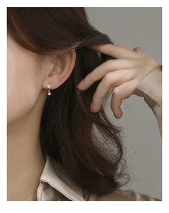 Detailed close-up of rose gold floral earrings with sparkling white crystals on a model