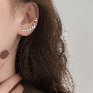 Close-up of curved silver ear cuff with double rows of white pearls and sparkling zircons