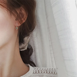 Close-up of 925 silver emerald zircon and pearl earrings worn by a model in soft light