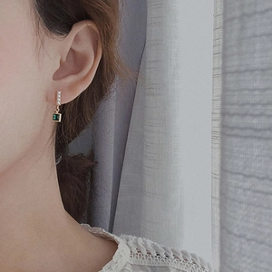 Close-up of 925 silver earrings with emerald green zircon and white pearls on ear