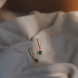 Detailed macro shot of vintage gold earrings with emerald zircon and small pearls