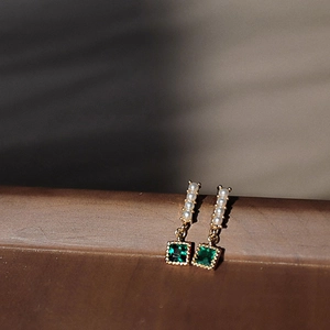 Detail of vintage gold earrings with vertical pearls and square emerald zircon stones