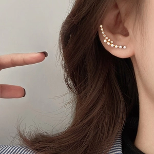 Elegant gold pearl ear cuff with zircon accents shown on ear, minimalist jewelry design