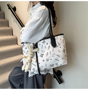 Side view of white printed tote bag with plush rabbit charm worn by a model