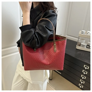 Close-up of red woven leather tote bag with brown slim straps and gold rivet detailing