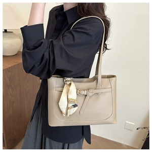 Detail of minimalist beige tote bag with buckle strap and decorative silk scarf handle