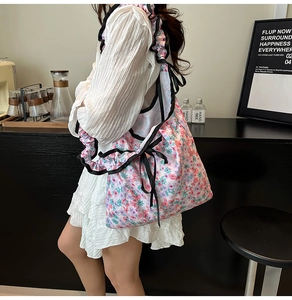 Close-up of floral canvas shoulder bag featuring ruffle straps and black ribbon bow detail