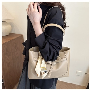 Model wearing a beige large tote bag with silk scarf detail and smooth leather finish