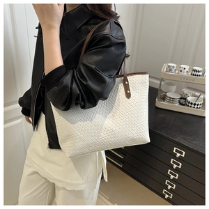 Detailed woven texture of a white tote bag with contrast brown leather handles and rivets
