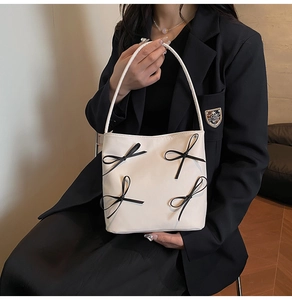 Detail einer cremeweißen Schultertasche aus Leder mit vier schwarzen Schleifen für Damen