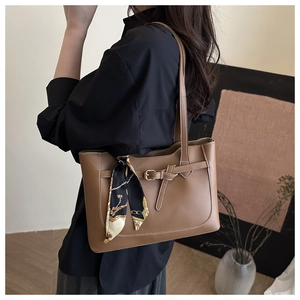 Detail view of caramel leather tote bag with silk scarf on a model for daily commute
