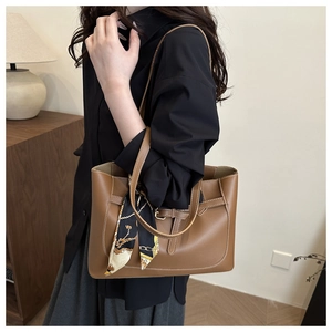 Detailed view of a brown leather tote bag with elegant silk scarf and buckle closure