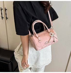 Detail of pink faux-snakeskin Boston bag with pearl bow and heart charm on a model