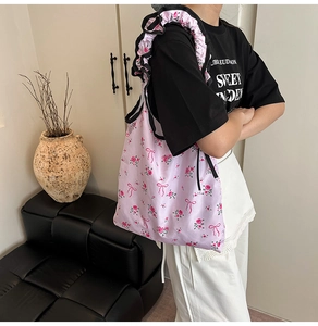 Detail of floral tote bag with pink bow prints and decorative ruffled black shoulder straps
