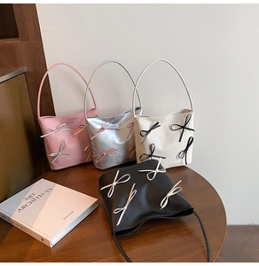 Detailed display of four elegant bow-accented handbags in pink, silver, white and black